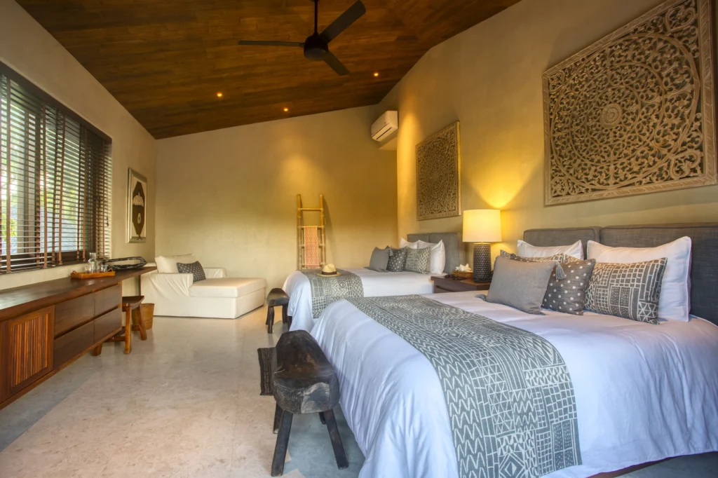 Guest bedroom at Casa Dewi with two beds, carved wall panels and a garden outlook