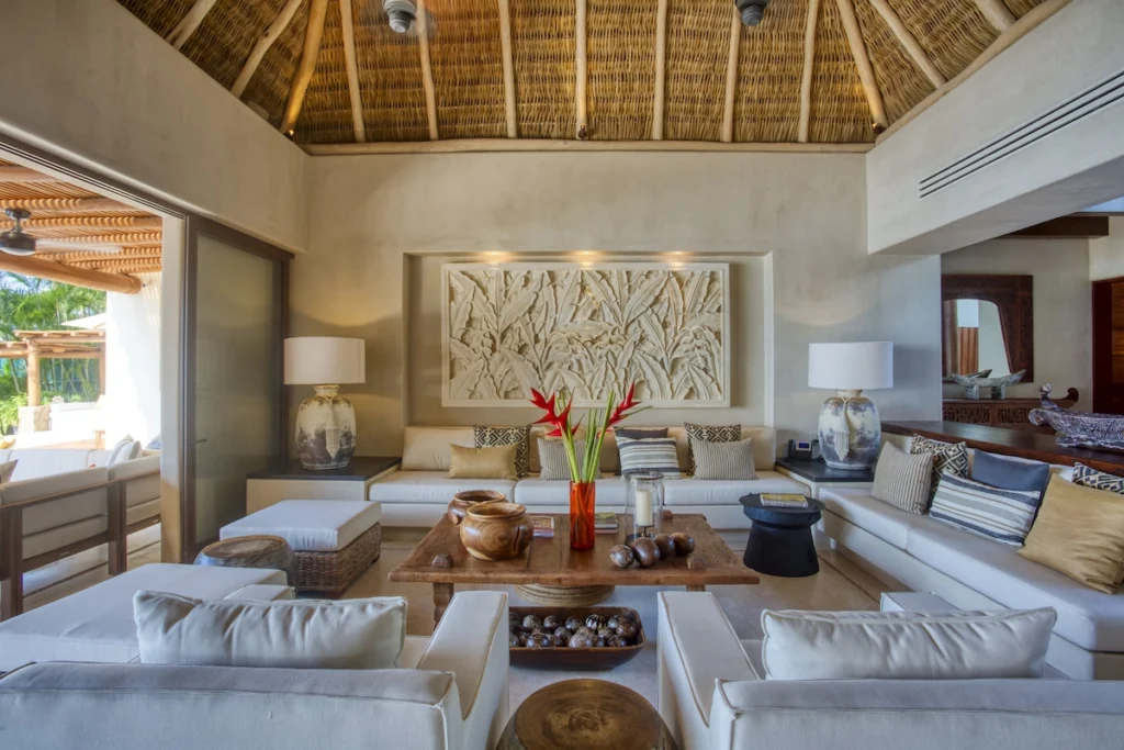 Main living room at Casa Dewi with white sofas, carved artwork and a palapa-style ceiling