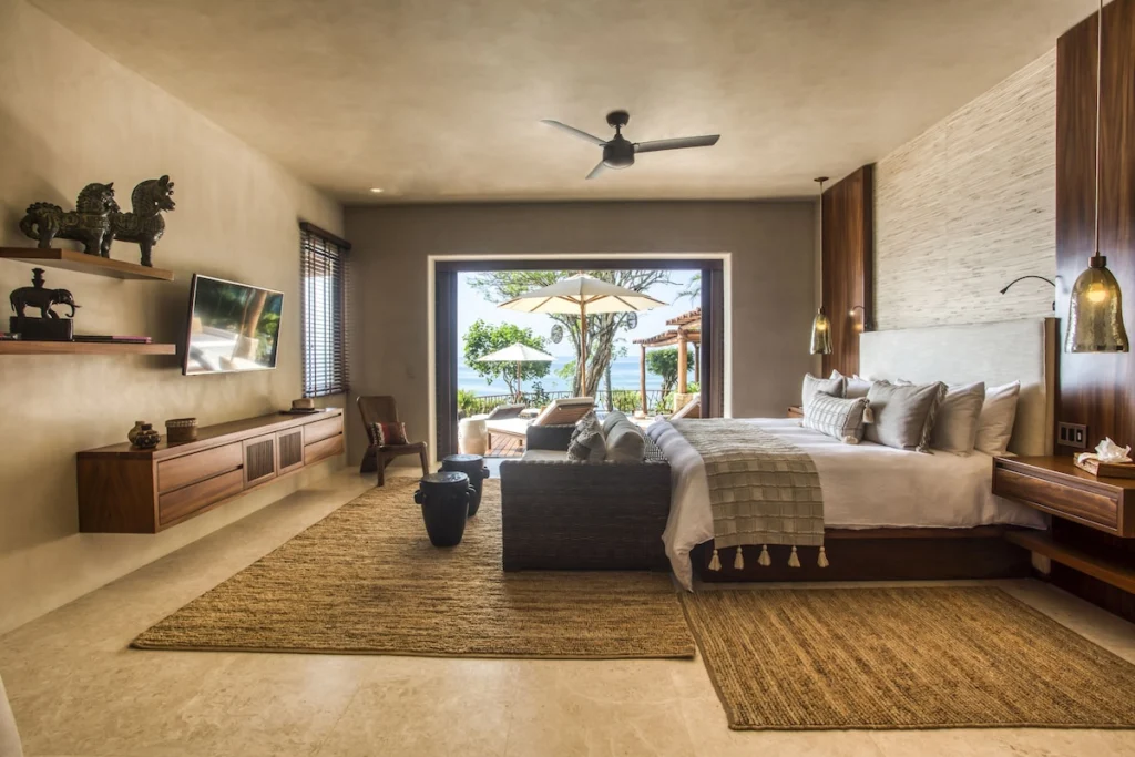 King bedroom at Casa Dewi opening to a private ocean-view terrace with loungers