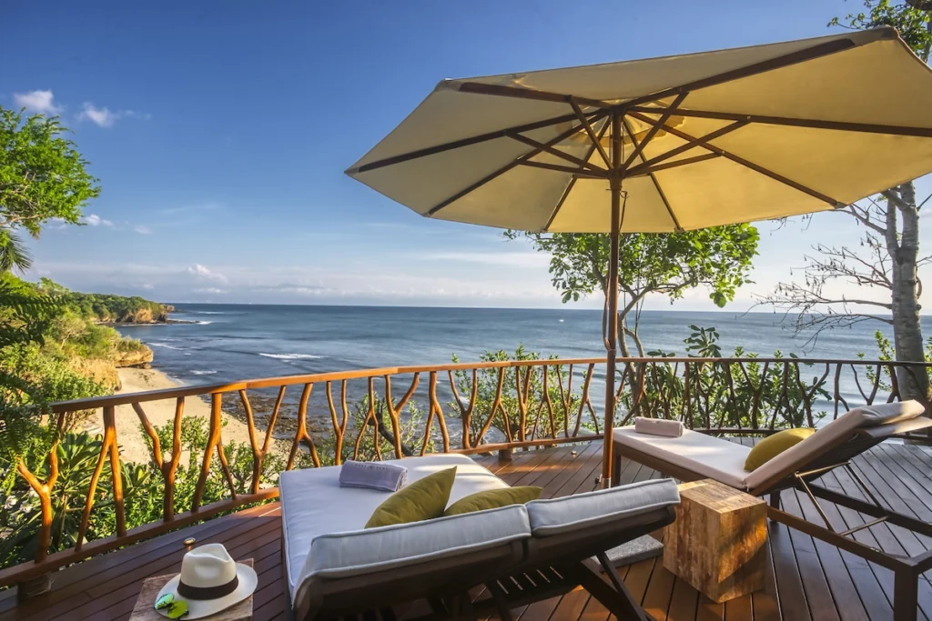 Private deck at Casa Dewi with an umbrella and loungers overlooking a sandy Pacific cove