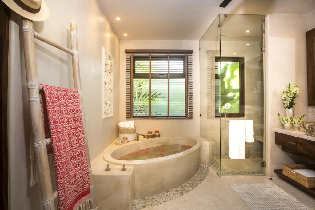 Bathroom at Casa Dewi with a round soaking tub, glass shower and natural-stone finishes
