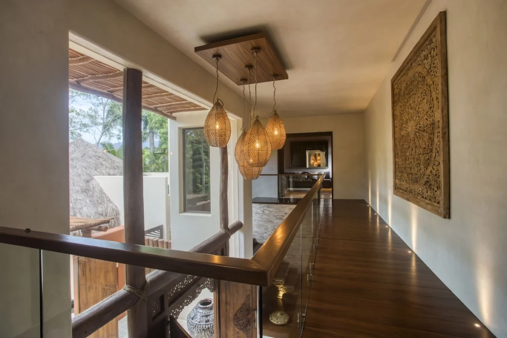 Upper gallery at Casa Dewi with woven pendant lights, glass railings and carved artwork