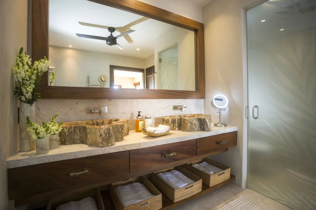 Double vanity at Casa Dewi with natural-stone vessel sinks and a glass shower