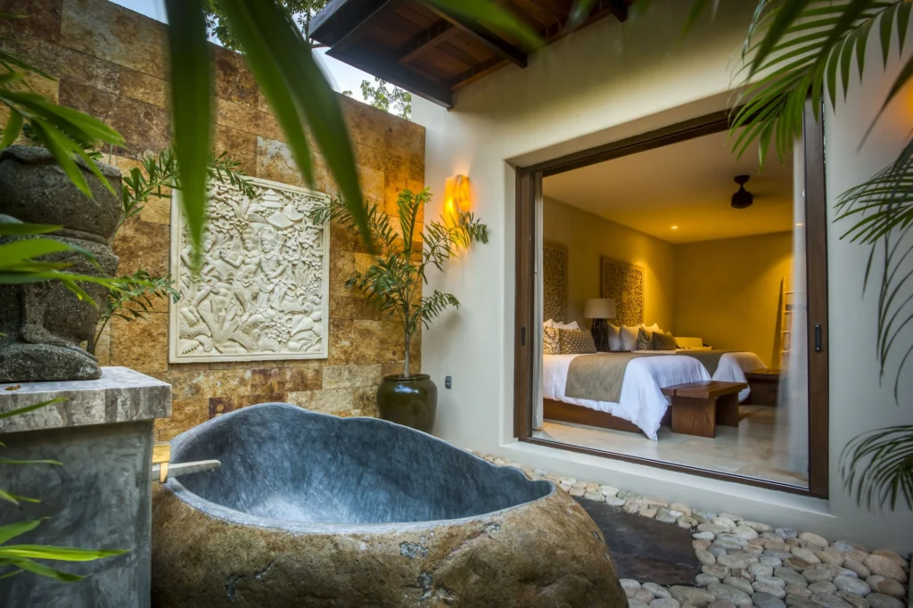 Private stone soaking tub in a tropical courtyard outside a Casa Dewi guest bedroom
