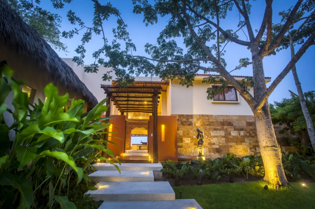 Illuminated garden entrance to Casa Dewi framed by mature tropical landscaping