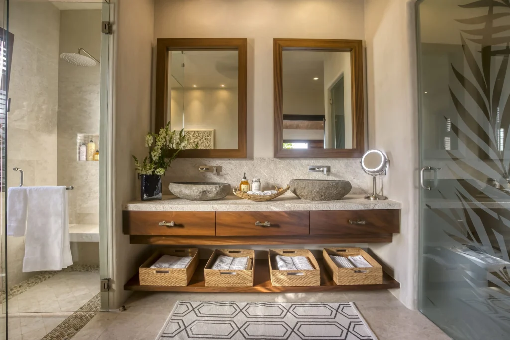 Bathroom at Casa Dewi with twin stone sinks and separate glass shower areas