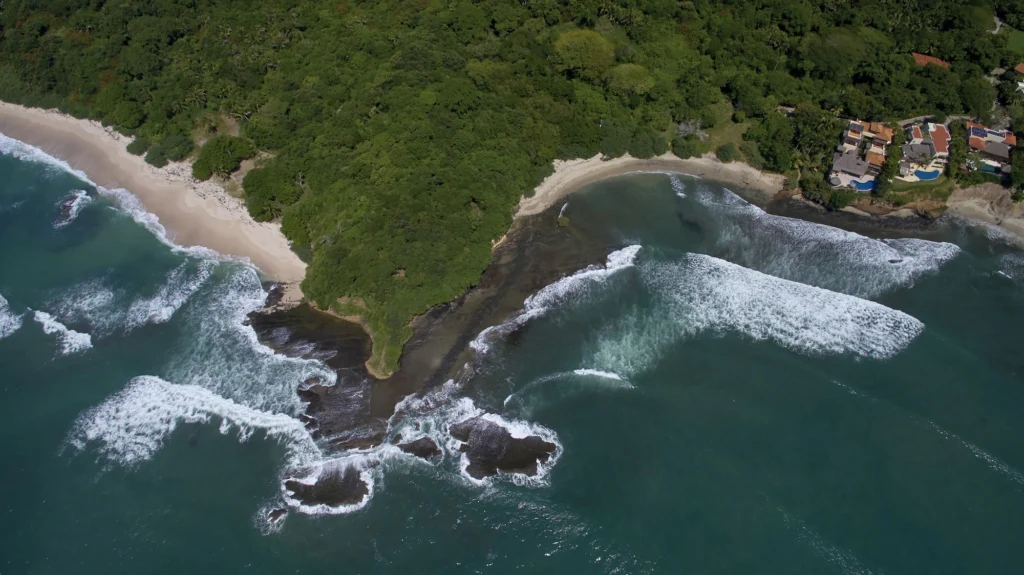 Aerial view of the rocky headland and two sandy coves beside Casa Dewi