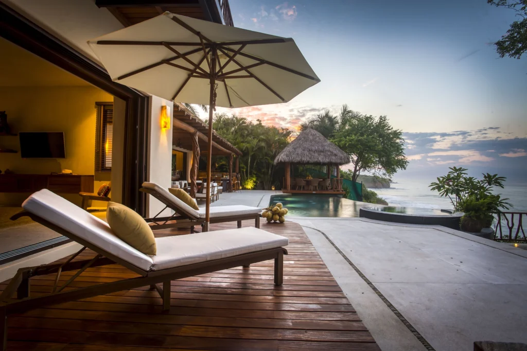 Sun loungers facing Casa Dewi's infinity pool and the Pacific at sunset