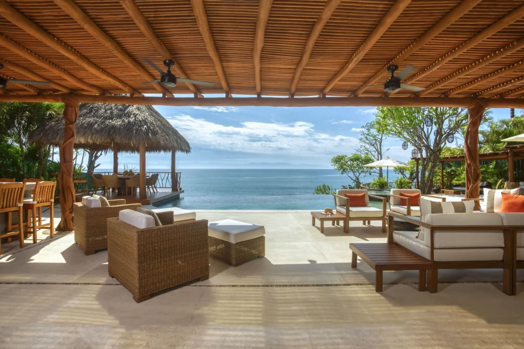 Open-air lounge at Casa Dewi framing the infinity pool, palapa pavilion and Pacific Ocean