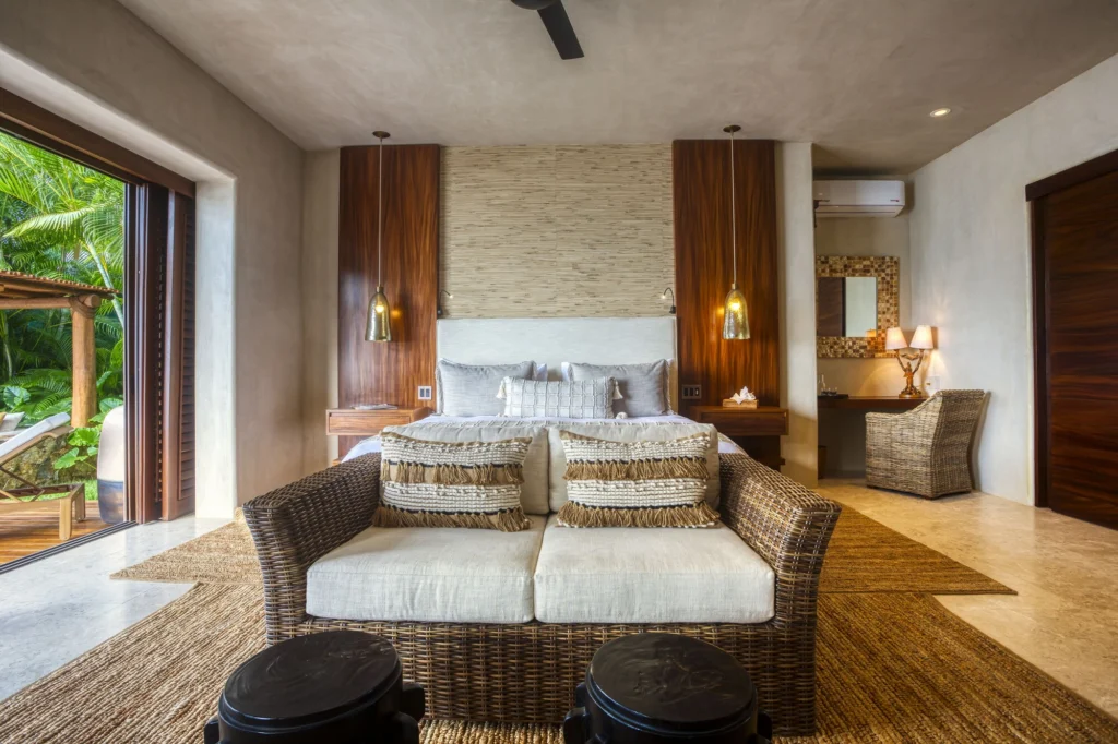 King bedroom at Casa Dewi with a wicker loveseat and doors opening toward the garden