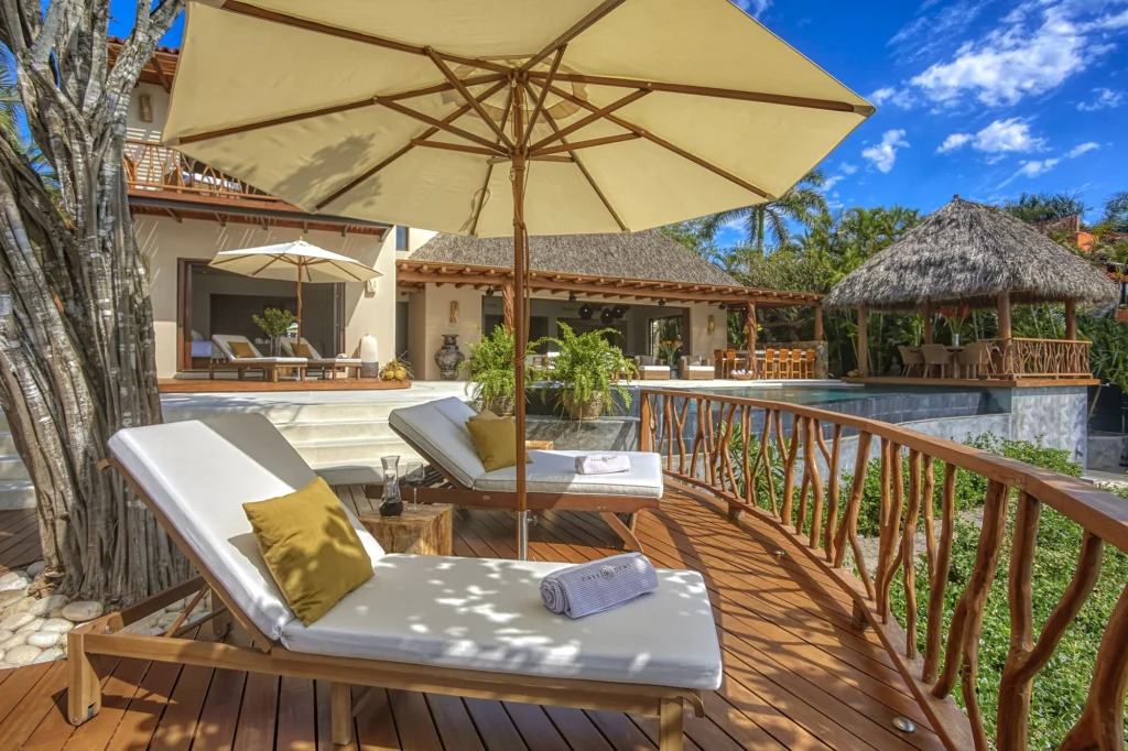 Wood sun deck with shaded loungers overlooking Casa Dewi's pool and palapa pavilion