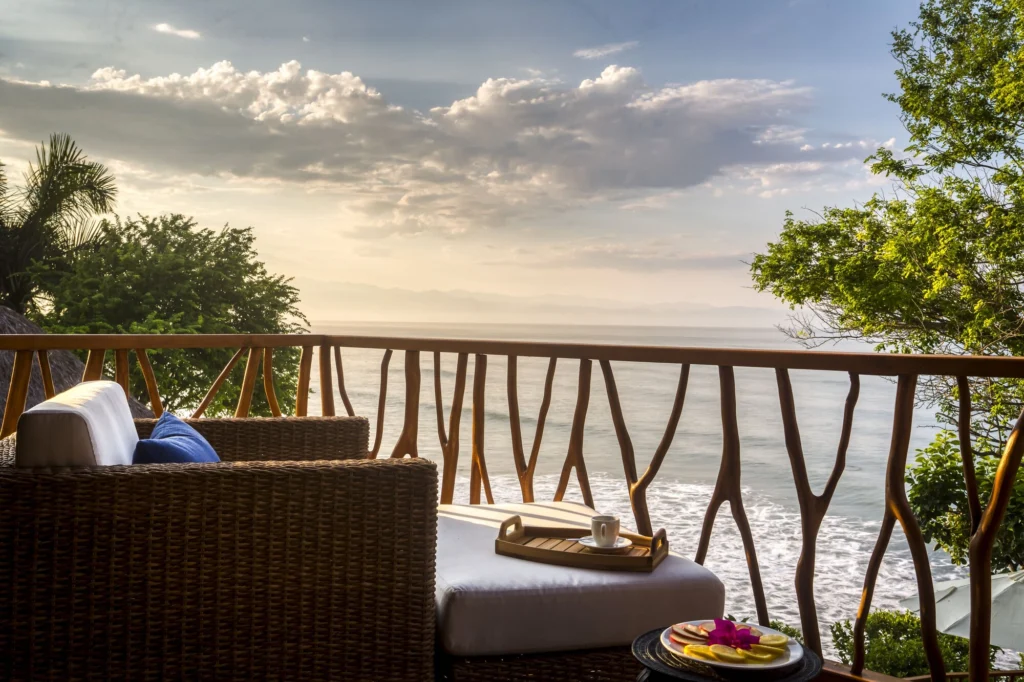 Ocean-view balcony seating at Casa Dewi with coffee and breakfast above the waves