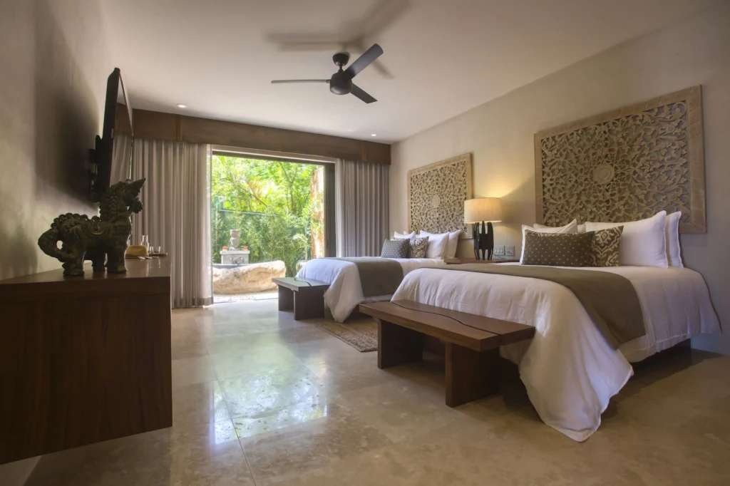 Guest bedroom at Casa Dewi with two beds and doors opening toward the tropical garden