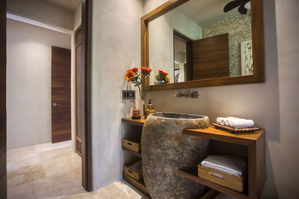 Powder room at Casa Dewi with a sculptural natural-stone sink and wood-framed mirror